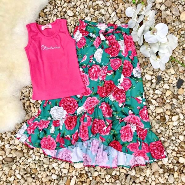 Uma roupa de menina com um top verde e rosa e uma saia.